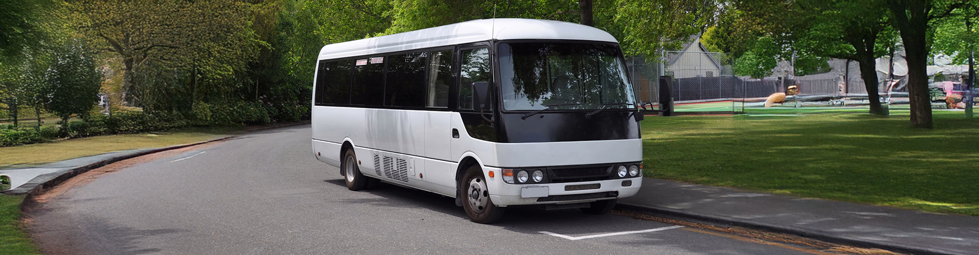 a white bus driving down a Virginia street next to trees