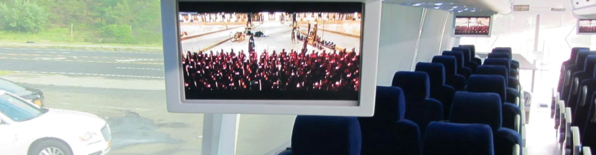 A television screen showing passengers enjoying a charter bus service