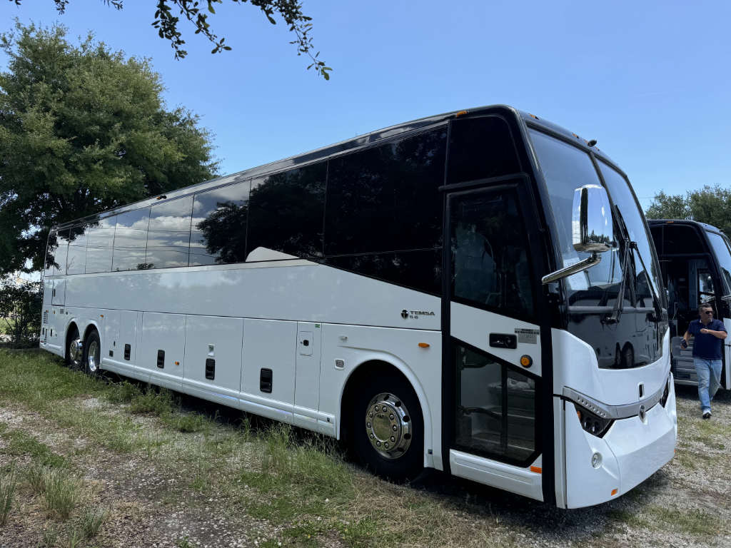 A large white bus in a North Carolina field for group trips