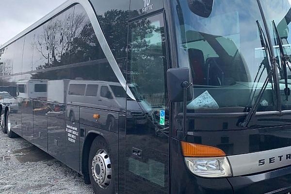 A bus parked in a wooded area for outdoor charter trips